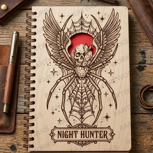 May include: A spiral-bound notebook with a light wood cover featuring a laser-engraved illustration of a spider with wings, a skull, and a crystal. The design includes a red circular cutout behind the skull and the text NIGHT HUNTER.