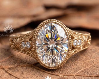 May include: A gold ring featuring a large oval-cut centre stone surrounded by a beaded bezel setting. The band displays intricate engraved scrollwork patterns and includes two small round accent stones on each side of the central setting.