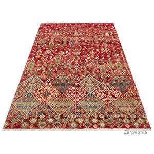 Peut inclure: Un tapis rectangulaire rouge avec un motif complexe de motifs floraux et g&eacute;om&eacute;triques. Le tapis pr&eacute;sente un champ central rouge avec des motifs d&eacute;taill&eacute;s en beige, bleu et or. La bordure a une frange blanche.