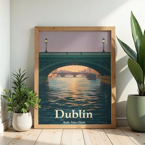 May include: A framed art print featuring a scenic view of Dublin, Ireland. The artwork depicts a bridge over a river with a sunset in the background. The word "Dublin" is prominently displayed at the bottom, with "Baile Átha Cliath" below it.