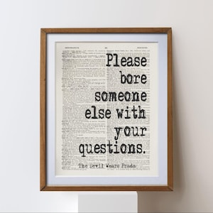 Könnte beinhalten: Gerahmter Druck mit dem Zitat "Please bore someone else with your questions" in schwarzer Schrift. Der Text befindet sich auf einem Vintage-Wörterbuchseiten-Hintergrund, gerahmt in einem braunen Holzrahmen.