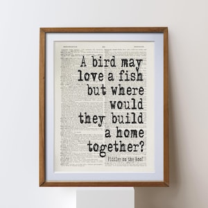 Może przedstawiać: Oprawiony wydruk z cytatem "A bird may love a fish but where would they build a home together?" w czarnym tekście. Tekst znajduje się na stronie ze starego słownika, w brązowej drewnianej ramie.