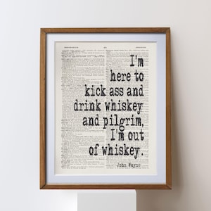 Peut inclure: Impression encadrée avec un fond de page de dictionnaire vintage. Le texte noir dit : "I'm here to kick ass and drink whiskey and pilgrim, I'm out of whiskey." La citation est attribuée à John Wayne. Le cadre est de couleur marron chaud.