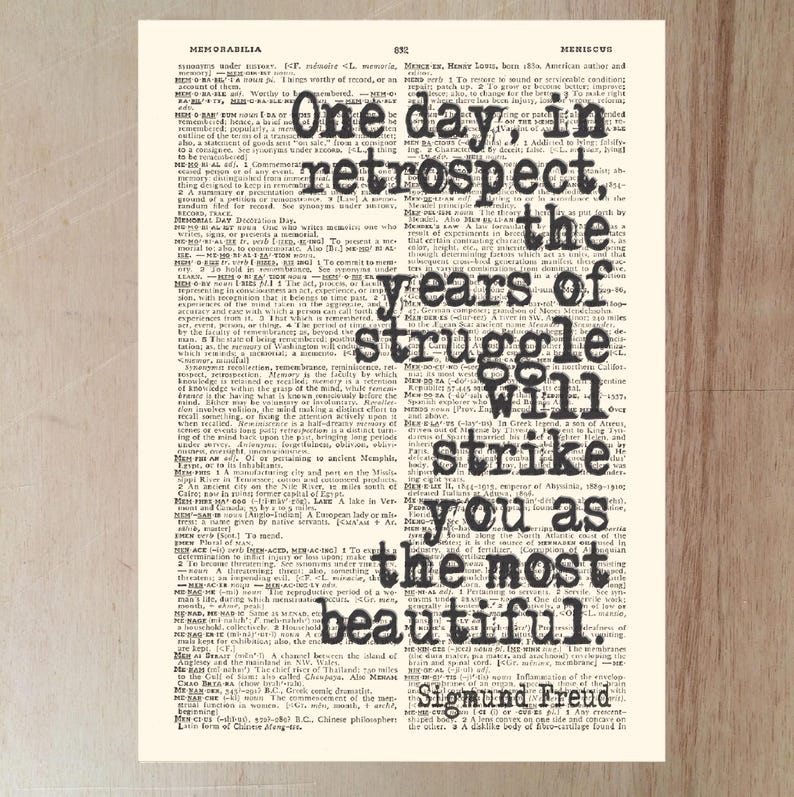 May include: Vintage print featuring a quote by Sigmund Freud: "One day, in retrospect, the years of struggle will strike you as the most beautiful." The text is in black, set against a cream-colored background of dictionary pages.