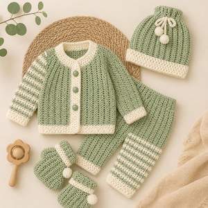 May include: A sage green and cream crochet set consisting of a long-sleeve button-up cardigan, matching pants, a beanie with two pom-poms, and a pair of booties. The cardigan and pants feature striped sleeves and legs with cream trim.