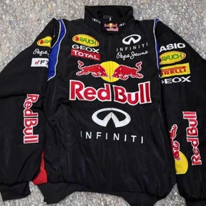 Puede incluir: Chaqueta de carreras Red Bull negra con múltiples logotipos de patrocinadores. La chaqueta presenta el logotipo de Red Bull de forma destacada en la parte delantera y en las mangas, junto con la marca Infiniti y Pepe Jeans. La chaqueta tiene una base negra con detalles rojos, blancos, amarillos y azules.