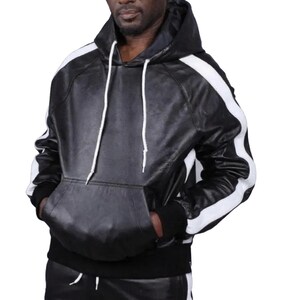 May include: Black leather hoodie with white stripes on the sleeves. The hoodie has a drawstring hood, a kangaroo pocket, and black ribbed cuffs and hem. The garment is made of leather.
