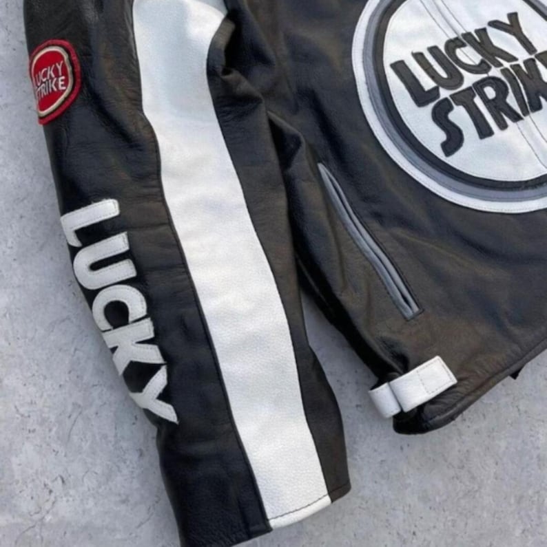 May include: Black leather jacket with white stripes and "LUCKY" printed on the sleeve. The jacket features a "LUCKY STRIKE" patch on the chest and sleeve. The jacket has a classic motorcycle style.