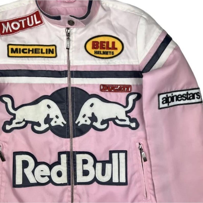 May include: Pink and white racing jacket with multiple sponsor patches, including "MOTUL", "MICHELIN", "BELL HELMETS", and "alpinestars". Features a "Red Bull" logo and "DUCATI" patch. The jacket has a zipper closure and a stand-up collar.