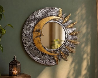 May include: A circular wall mirror featuring a crescent moon and sun motif. The moon is finished in gold with a facial profile, while the surrounding frame displays intricate silver and gold swirling patterns and sun rays extending outward.