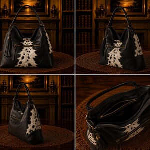 May include: Black and white leather hobo bag with a cowhide pattern. The bag features a top handle, a zipper closure, and a decorative tassel. The bag is sitting on a round, woven mat.