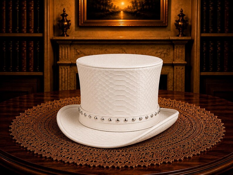 Puede incluir: Un sombrero de copa blanco con un patr&oacute;n texturizado y una banda con tachuelas descansa sobre un tapete marr&oacute;n adornado. El sombrero se exhibe sobre una mesa de madera oscura, con una chimenea y estanter&iacute;as en el fondo.