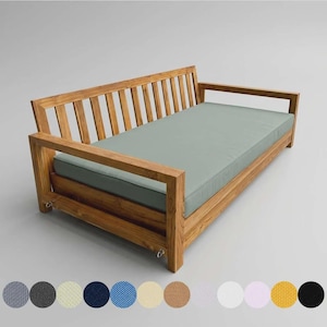 May include: A wooden daybed with a light green cushion. The frame is made of light brown wood with a slatted back and armrests. The daybed is shown against a plain background, with a selection of fabric swatches below.
