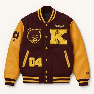 May include: A maroon and gold varsity jacket with leather sleeves. The jacket features a bear head patch, the name "Kanye", the letter "K", and the number "04" in gold. The jacket has a striped collar, cuffs, and hem.