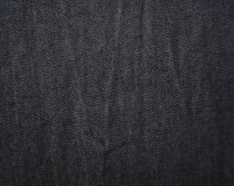 May include: Close-up of a dark blue denim fabric with a textured weave.