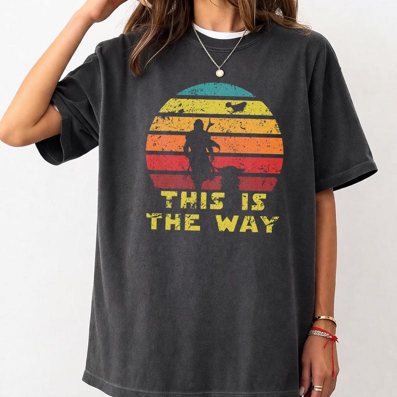 Vintage distressed retro sunset graphic featuring a galactic warrior silhouette with the quote “This Is The Way” on a dark t-shirt design in bootleg vintage style.