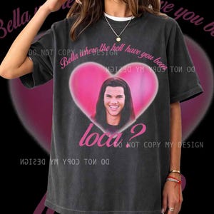 Peut inclure: T-shirt gris foncé avec un cœur rose et une photo d'une personne souriante. Le t-shirt porte les phrases "Bella where the hell have you been" et "Loca ?". Les mots "DO NOT COPY MY DESIGN" sont également imprimés sur le t-shirt.