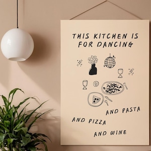 Puede incluir: Un estampado de arte mural beige con ilustraciones en negro de una bola de discoteca, copas de vino, pasta, pizza y flores. El texto dice: "THIS KITCHEN IS FOR DANCING AND PASTA AND PIZZA AND WINE."