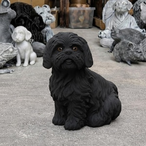 May include: A black Shih Tzu dog statue with detailed fur texture and brown eyes. The dog is in a sitting position, with other stone animal sculptures in the background. The statue is made of a dark material.