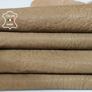 Può includere: Primo piano di pelli di cuoio impilate, di colore beige. La pelle ha una superficie strutturata e rugosa. L'immagine include un logo con la scritta "ITALIAN SKINS".