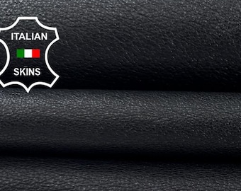May include: Close-up of folded black leather. The leather has a textured surface and appears to be high-quality. The image includes a logo that says "Italian Skins". The leather is likely used for crafting items like bags, wallets, or upholstery.