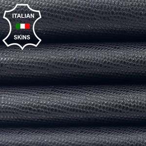 May include: Close-up of stacked, dark gray leather sheets with a textured surface. The leather has a subtle, repeating pattern. The image includes a logo with the text "ITALIAN SKINS".