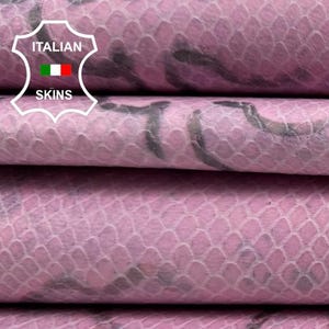 Puede incluir: Primer plano de hojas de cuero rosa apiladas con una textura de reptil y patrones florales gris oscuro. El cuero tiene un brillo sutil. La imagen incluye el texto "ITALIAN SKINS".