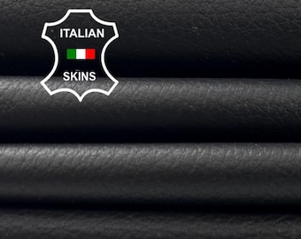May include: Close-up of stacked black leather sheets. The leather has a textured surface and is folded over itself. The image includes a logo with the text "ITALIAN SKINS" and the Italian flag.