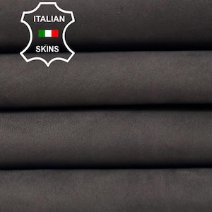 May include: Close-up of four stacked rolls of dark gray leather. The leather has a soft, matte finish. The Italian Skins logo is visible in the upper left corner.