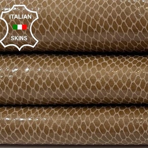 Puede incluir: Tres piezas de cuero marrón con un patrón texturizado, similar a la piel de serpiente. El cuero está apilado uno encima del otro. Una etiqueta con el texto "ITALIAN SKINS" es visible en la esquina superior izquierda de la imagen.