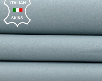 May include: Three pieces of light blue leather stacked on top of each other. The leather is smooth and has a slight sheen. The leather is labeled "ITALIAN SKINS".