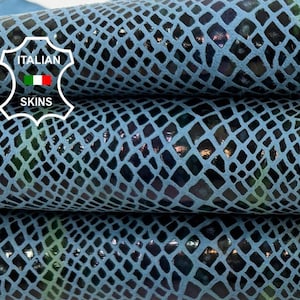 Puede incluir: Primer plano de pieles de cuero texturizadas apiladas. El cuero tiene un fondo azul claro con un patrón de diamantes azul oscuro. Se ven toques de verde y dorado dentro del patrón. El logotipo de Italian Skins está en la esquina superior izquierda.