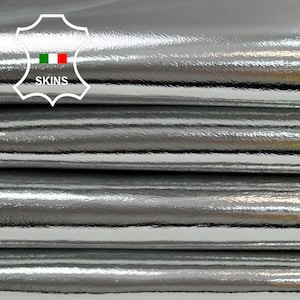 May include: Close-up of a stack of silver metallic leather. The leather has a smooth, shiny finish.