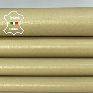 May include: Four rolls of beige leather, labeled "ITALIAN SKINS", are stacked on a white surface.