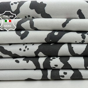 May include: Close-up of a stack of gray fabric with a black and white abstract pattern. The fabric is folded neatly and has a label that reads "ITALIAN SKINS".