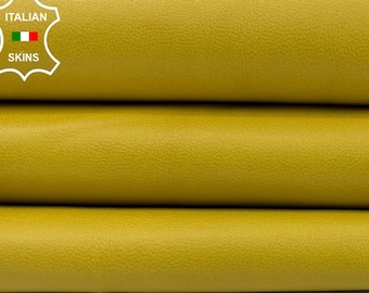 May include: Close-up of three stacked rolls of mustard-yellow leather. The leather has a smooth, matte finish and appears to be high-quality. The image is well-lit, highlighting the texture and color of the material. The Italian Skins logo is in the upper left corner.