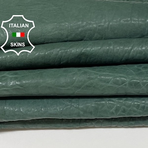 Può includere: Primo piano di una pila di pelli di cuoio verde. La pelle ha una superficie testurizzata ed è piegata in tre. L'etichetta "ITALIAN SKINS" è visibile nell'angolo in alto a sinistra.
