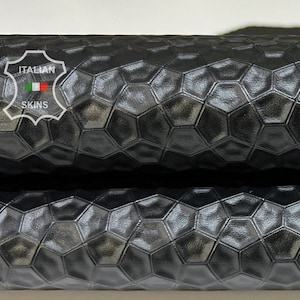 May include: Close-up of black leather with a hexagonal embossed pattern. The leather is folded in half, showing the texture from both sides.