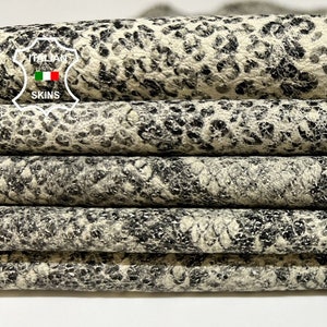 May include: Close-up of a stack of black and white patterned leather. The leather has a textured surface and a leopard print design.