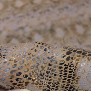 Op de afbeelding: Close-up van een stuk bruin slangenleer met een subtiele glans. Het leer heeft een getextureerd patroon van schubben.