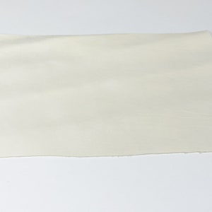 K&ouml;nnte beinhalten: Ein St&uuml;ck cremefarbenes Leder, das die nat&uuml;rliche Maserung der Haut zeigt. Das Leder ist glatt und geschmeidig, mit einem leichten Glanz. Es ist ein hochwertiges Leder, das sich ideal f&uuml;r die Herstellung einer Vielzahl von Lederwaren eignet.