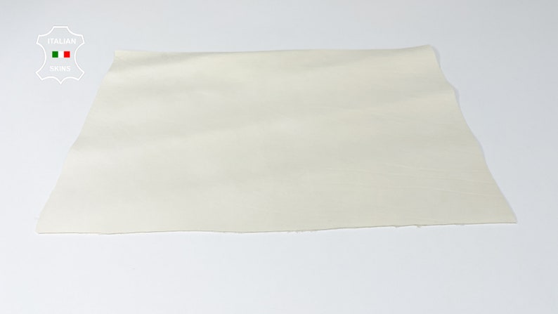 K&ouml;nnte beinhalten: Ein St&uuml;ck cremefarbenes Leder, das die nat&uuml;rliche Maserung der Haut zeigt. Das Leder ist glatt und geschmeidig, mit einem leichten Glanz. Es ist ein hochwertiges Leder, das sich ideal f&uuml;r die Herstellung einer Vielzahl von Lederwaren eignet.