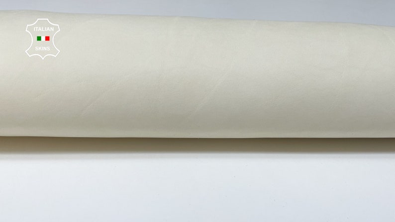 K&ouml;nnte beinhalten: Nahaufnahme einer Rolle cremefarbener Leder. Das Leder ist glatt und hat einen leichten Glanz. Das Etikett auf der Rolle lautet "ITALIAN SKINS".