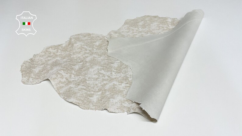 May include: A piece of off-white leather with a textured surface. The leather is folded over to show the smooth underside.