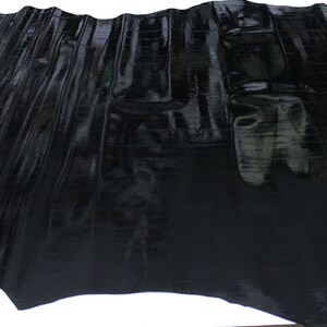 May include: Black alligator skin hide with a glossy finish. The hide is folded and shows the texture of the skin.