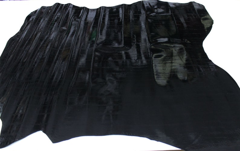 May include: Black alligator skin hide with a glossy finish. The hide is folded and shows the texture of the skin.