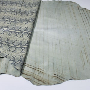 May include: A piece of light blue leather with a snakeskin pattern on one side and a smooth, textured surface on the other side.