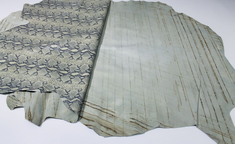 May include: A piece of light blue leather with a snakeskin pattern on one side and a smooth, textured surface on the other side.