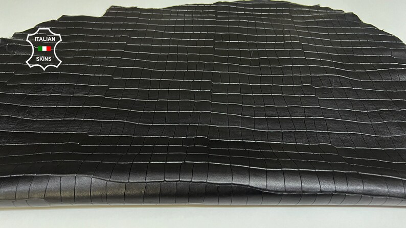 May include: Black leather with a square embossed pattern. The leather is folded in half and has a label that reads "ITALIAN SKINS" with a small Italian flag.