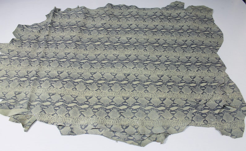 May include: A piece of light green snakeskin with a dark gray snake pattern.